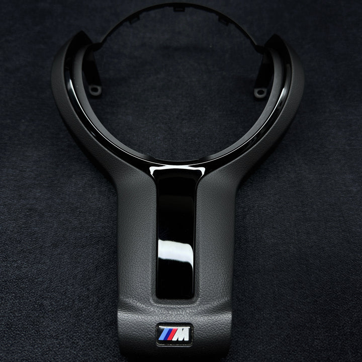 A black steering wheel trim with the BMW M brand logo in the center.