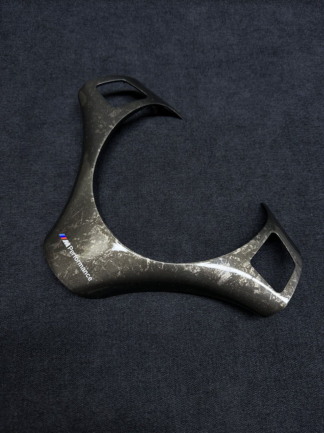 A forged carbon style steering wheel trim with a textured finish, branded with Performance BMW