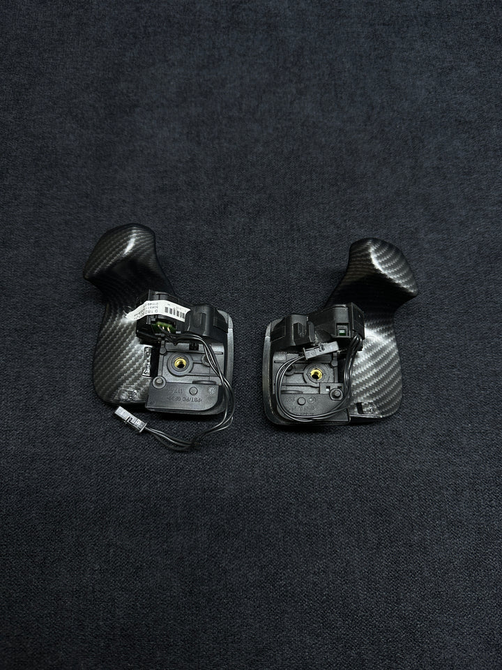 A pair of matte carbon style shift paddles for a BMW vehicle