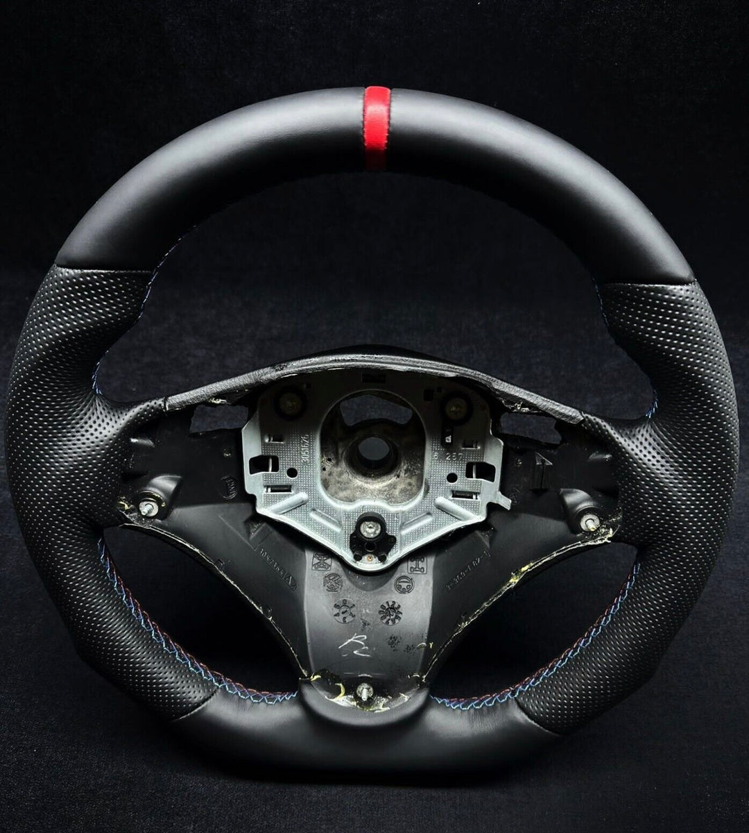  black perforated leather steering wheel with a red stripe and M stitching, designed for BMW vehicles showing the flat bottom design 