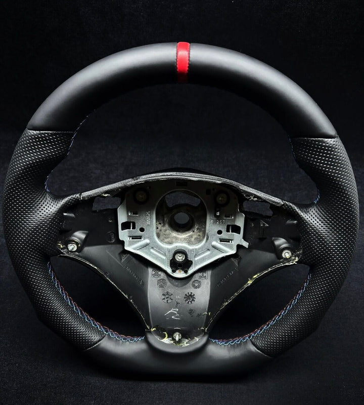  black perforated leather steering wheel with a red stripe and M stitching, designed for BMW vehicles showing the flat bottom design 