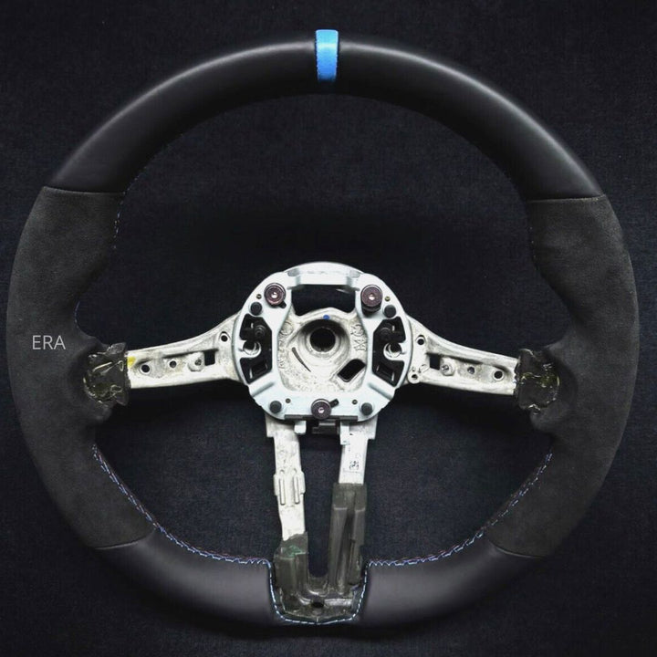 Custom bmw aftermarket black leather steering wheel with a light blue stripe and M stitching, showing the inner side with multiple buttons and a metal shaft.