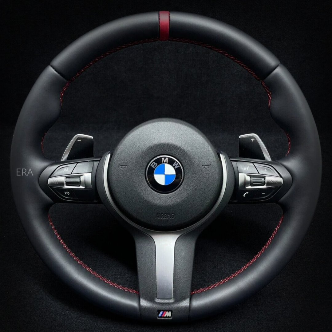 Custom steering wheel for BMW with red stitching, black leather, and shift paddles.