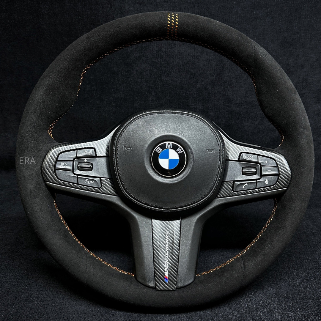 BMW steering wheel with black leather and carbon fiber accents on a dark background