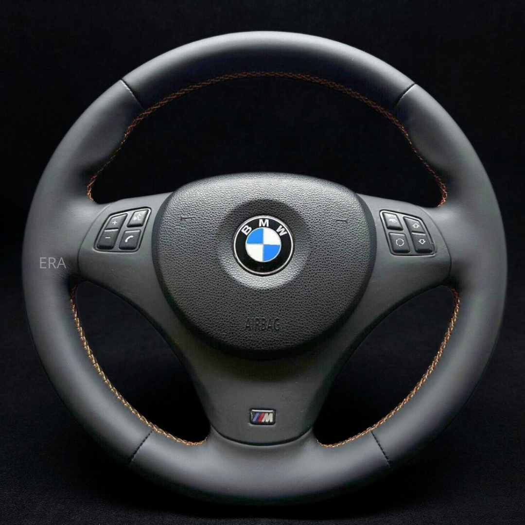 Custom steering wheel for BMW with black Nappa leather trim and orange stitching, without airbag or shift paddles.
